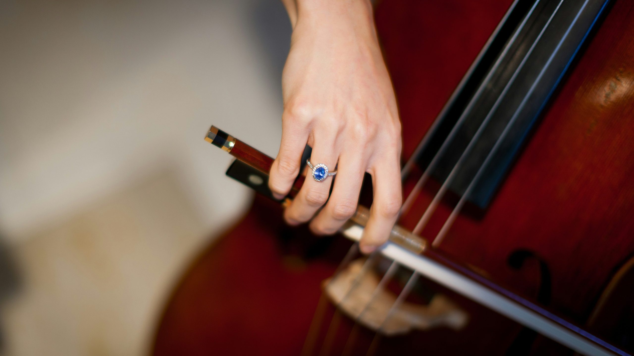 photographie d'une main portant une bague qui joue du violoncelle