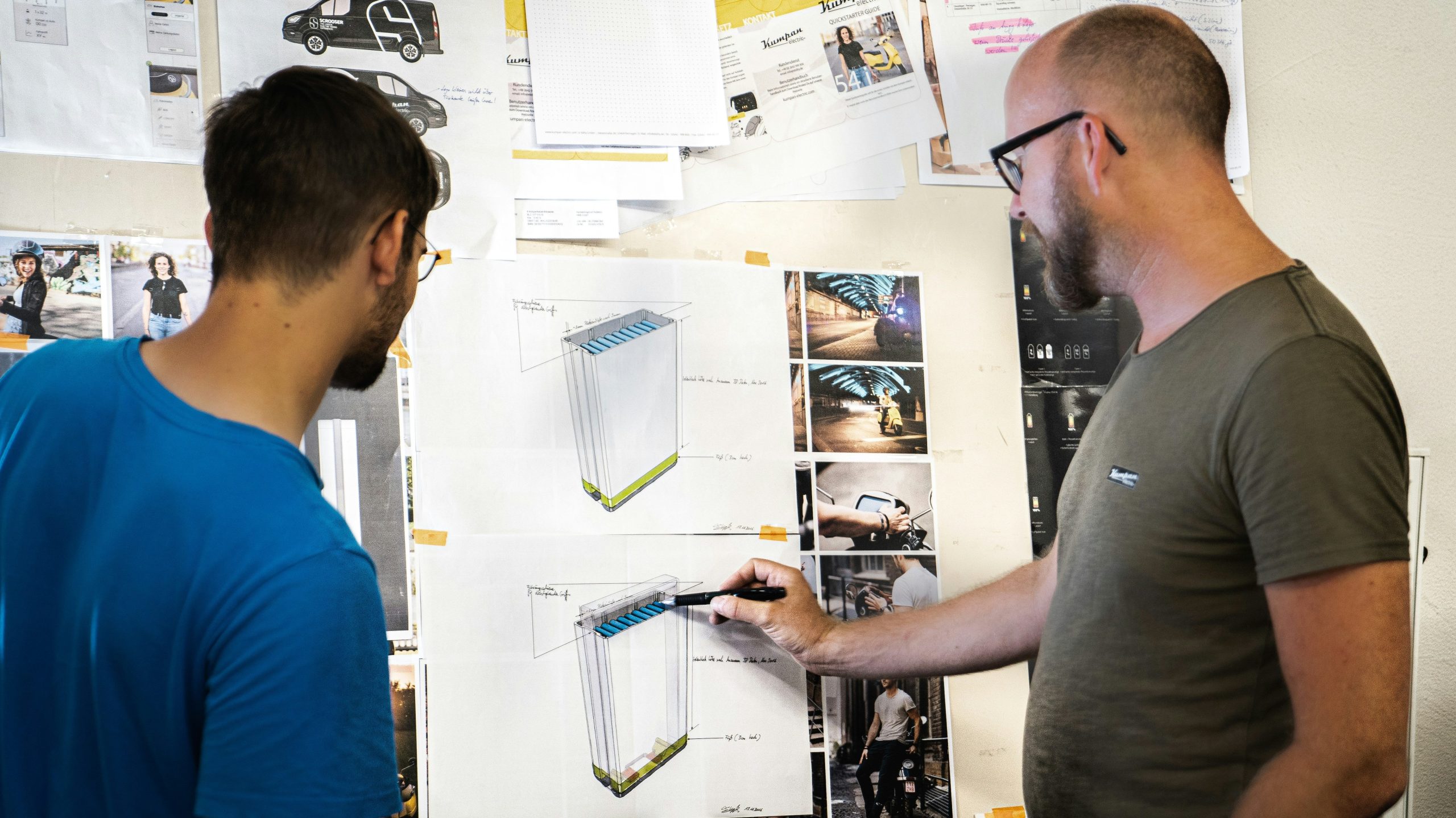 deux hommes devant un tableau de papier. L'un tient un stylo