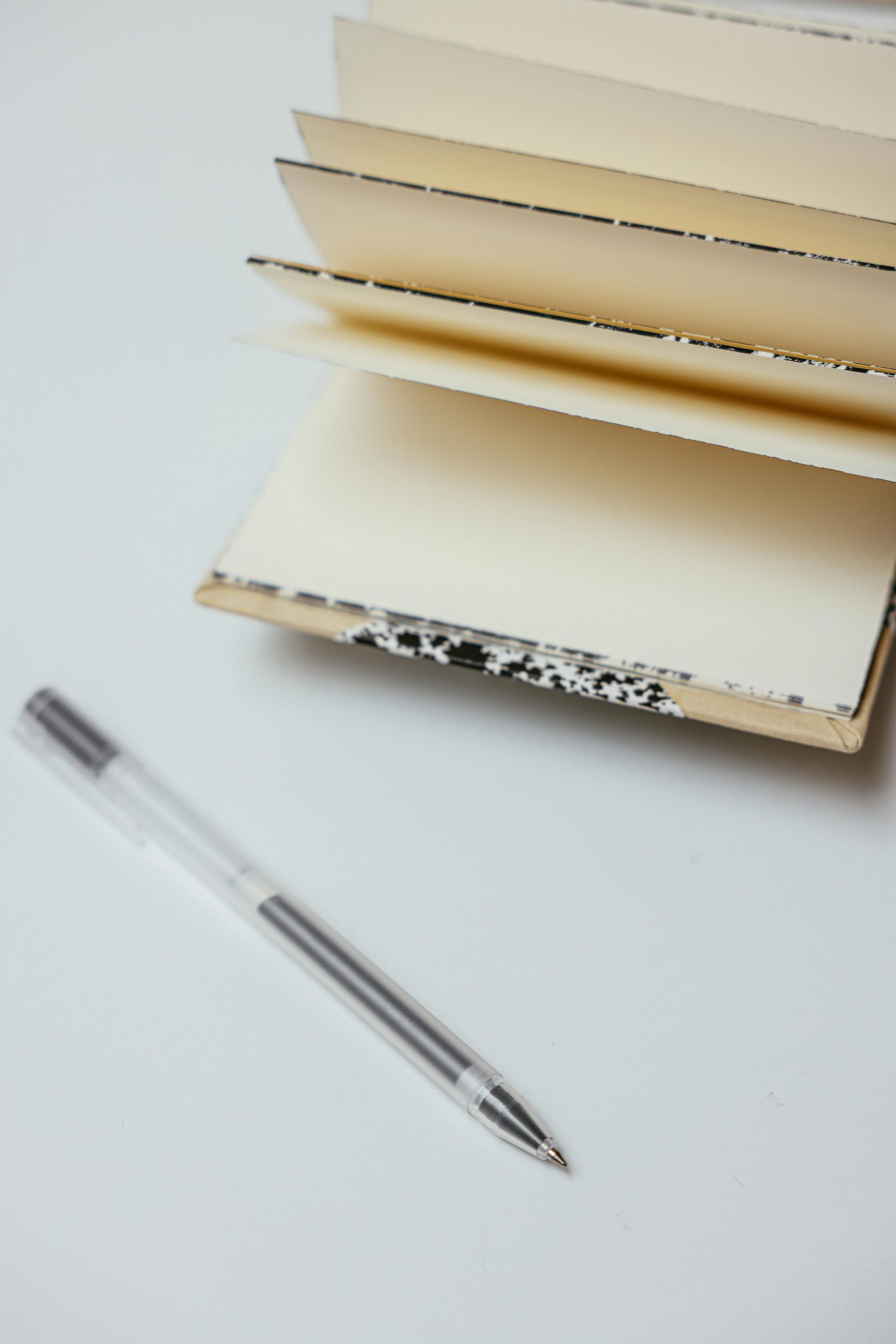 Minimalist setup of an open notebook and pen on a white surface, perfect for writers.